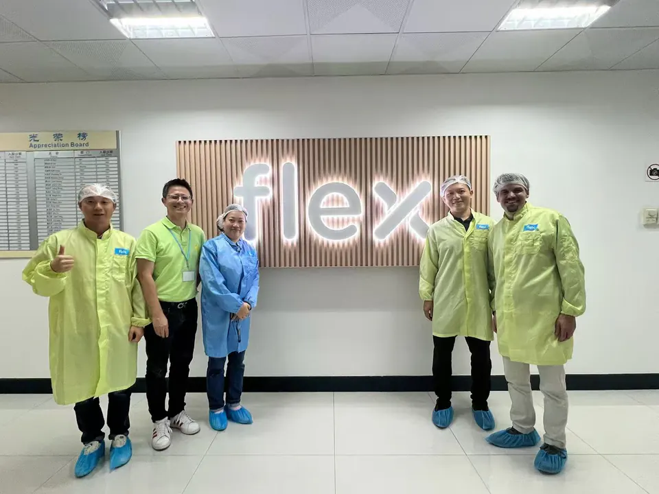 Charley 与参访人员在 Flex 标识前合影